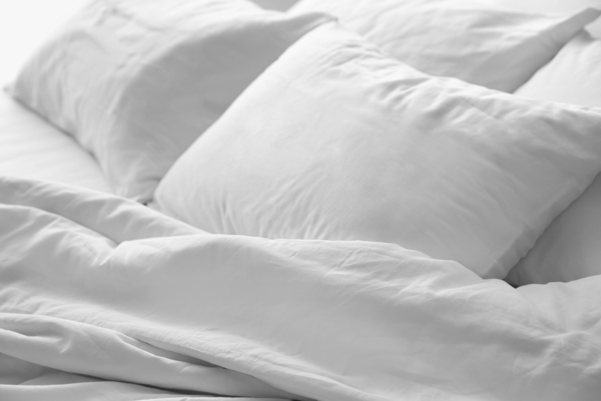 Two white pillows on all white bed.