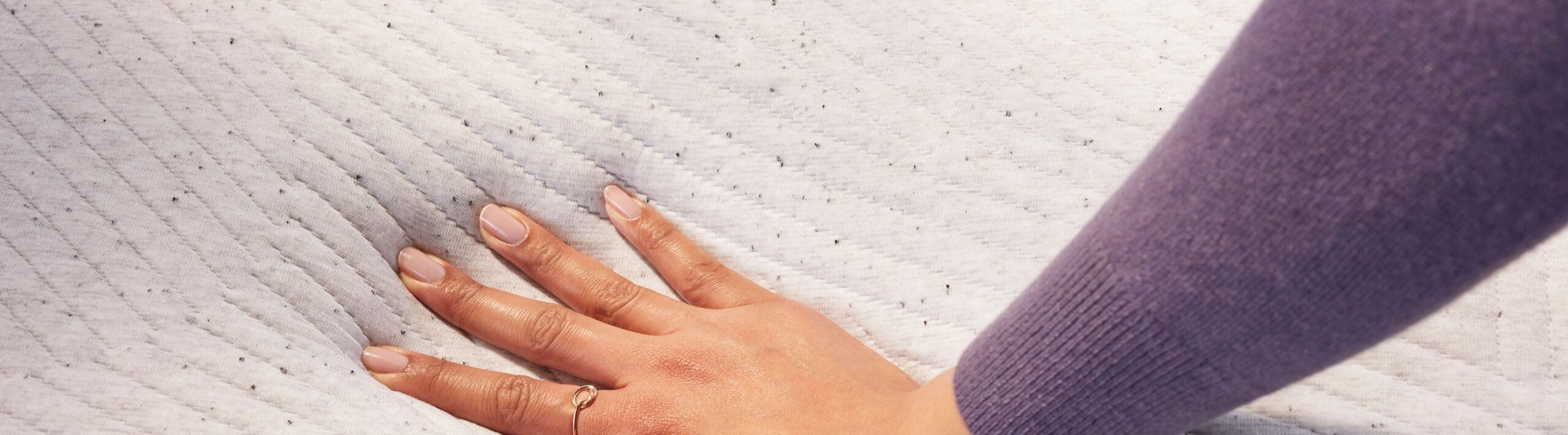 womans hand sinking into soft mattress