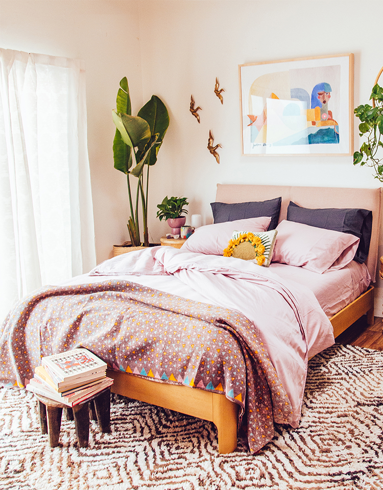 bedroom with pink sheets, plants, and wall decor