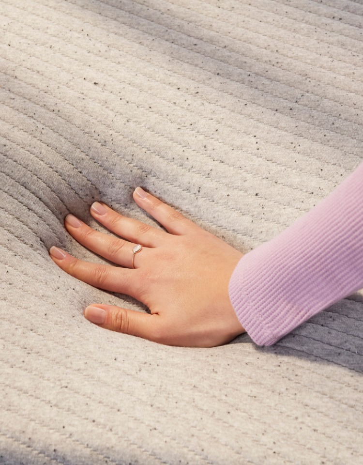 Woman's hand pushing down the memory foam mattress