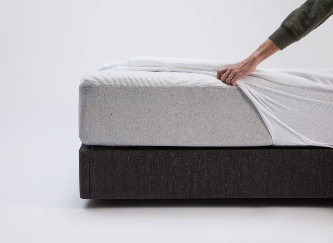 Man putting a mattress protector on a bed