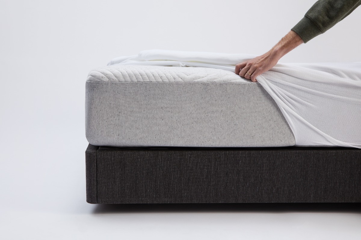 Man putting a mattress protector on a bed