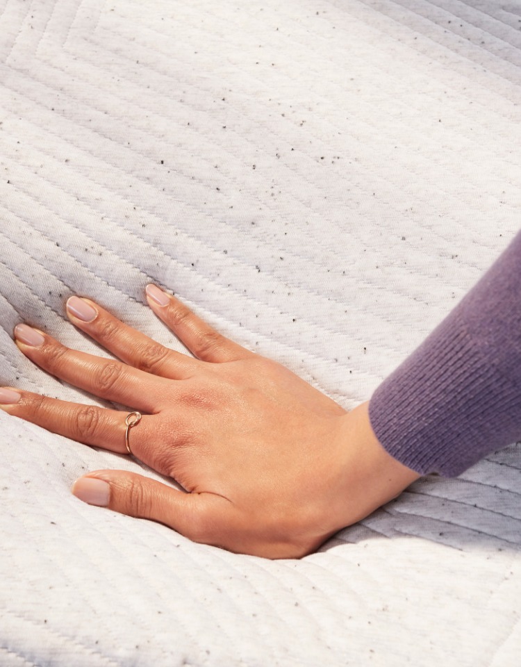 womans hand sinking into soft mattress